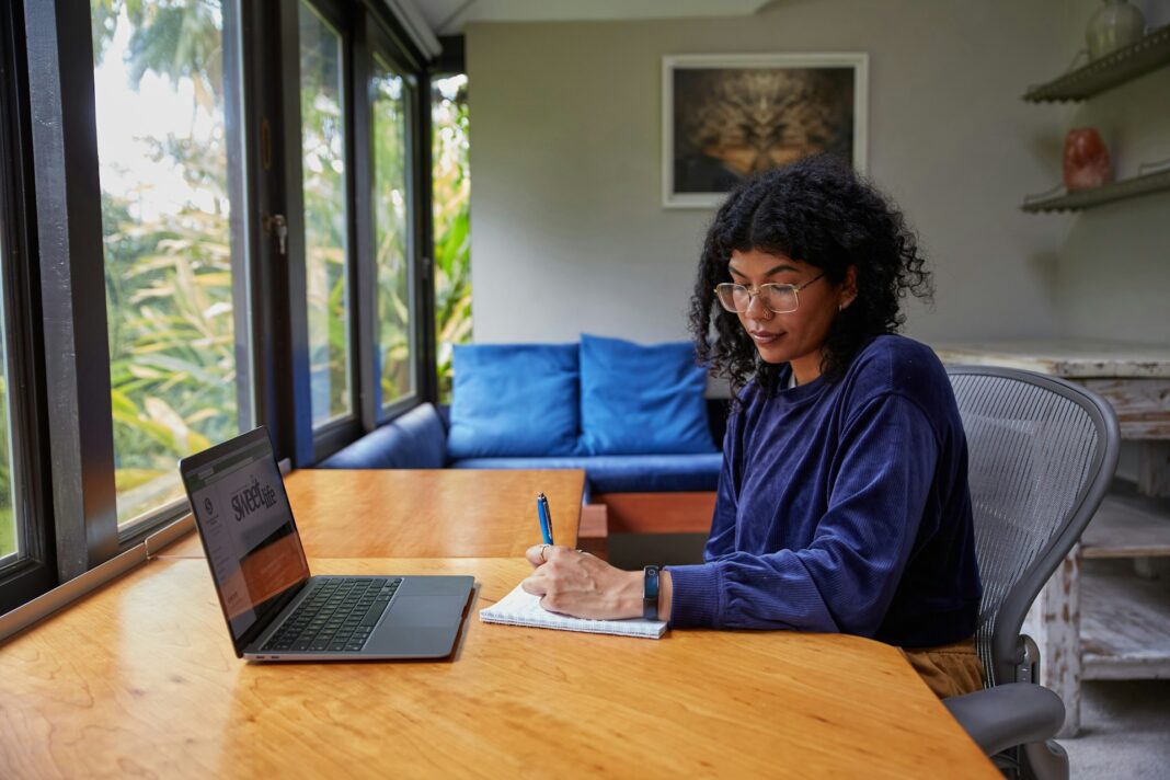African American woman sitting at desk in home office looking at notepad
