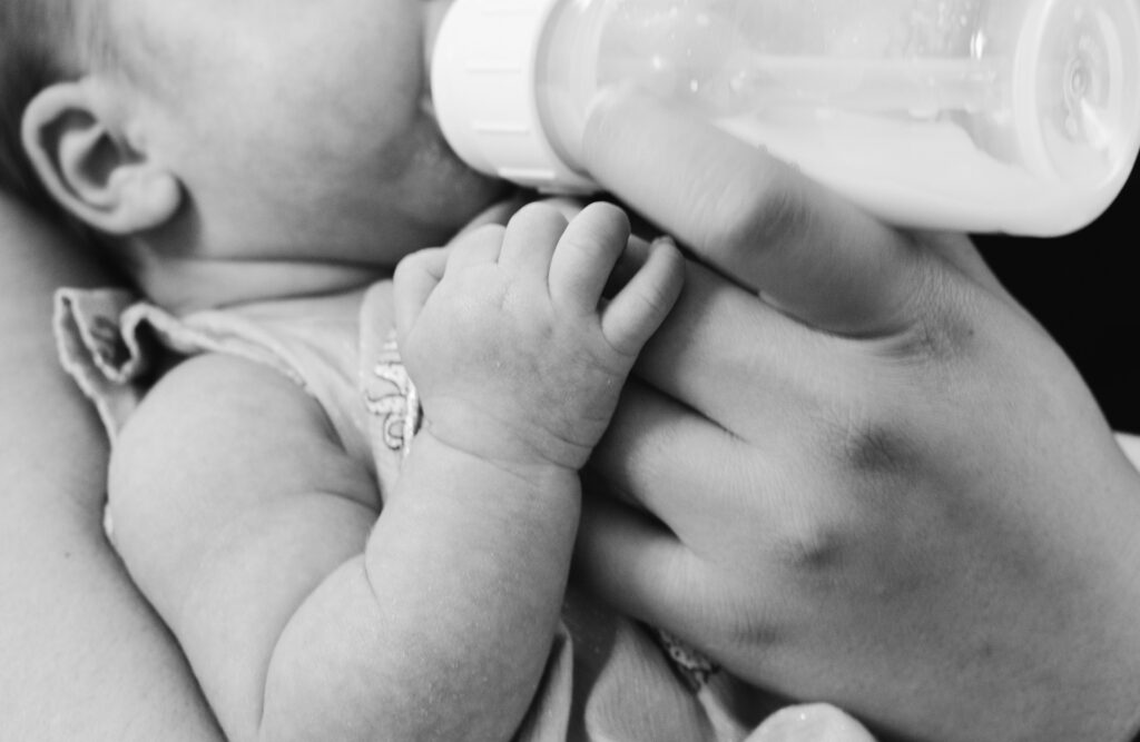 Baby drinking formula and being held in mother's arms